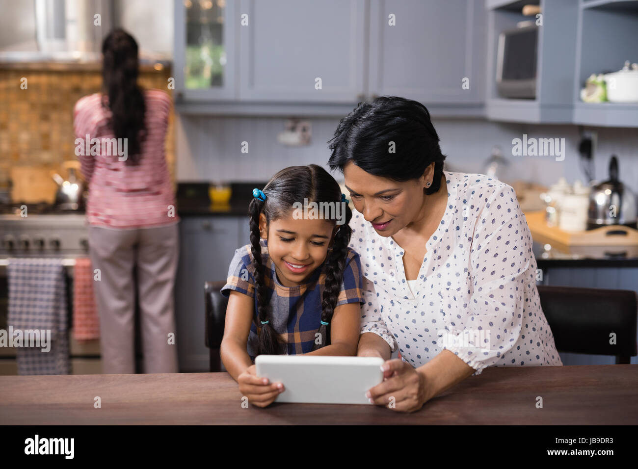 Nonna e nipote con tavoletta digitale insieme nella cucina di casa Foto Stock