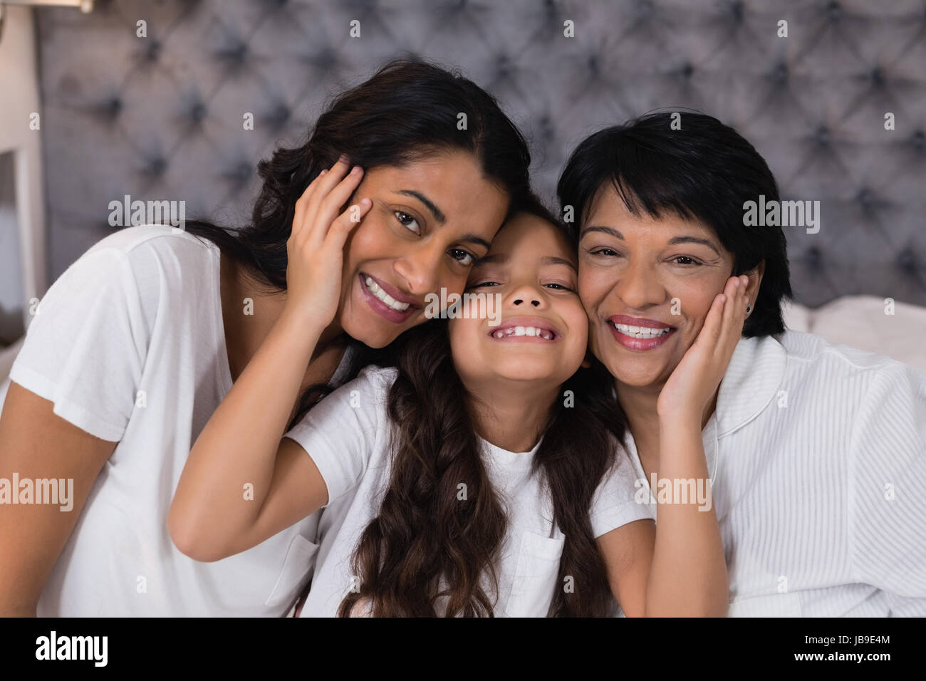 Ritratto di sorridere multi-generazione abbracciando il letto di casa Foto Stock