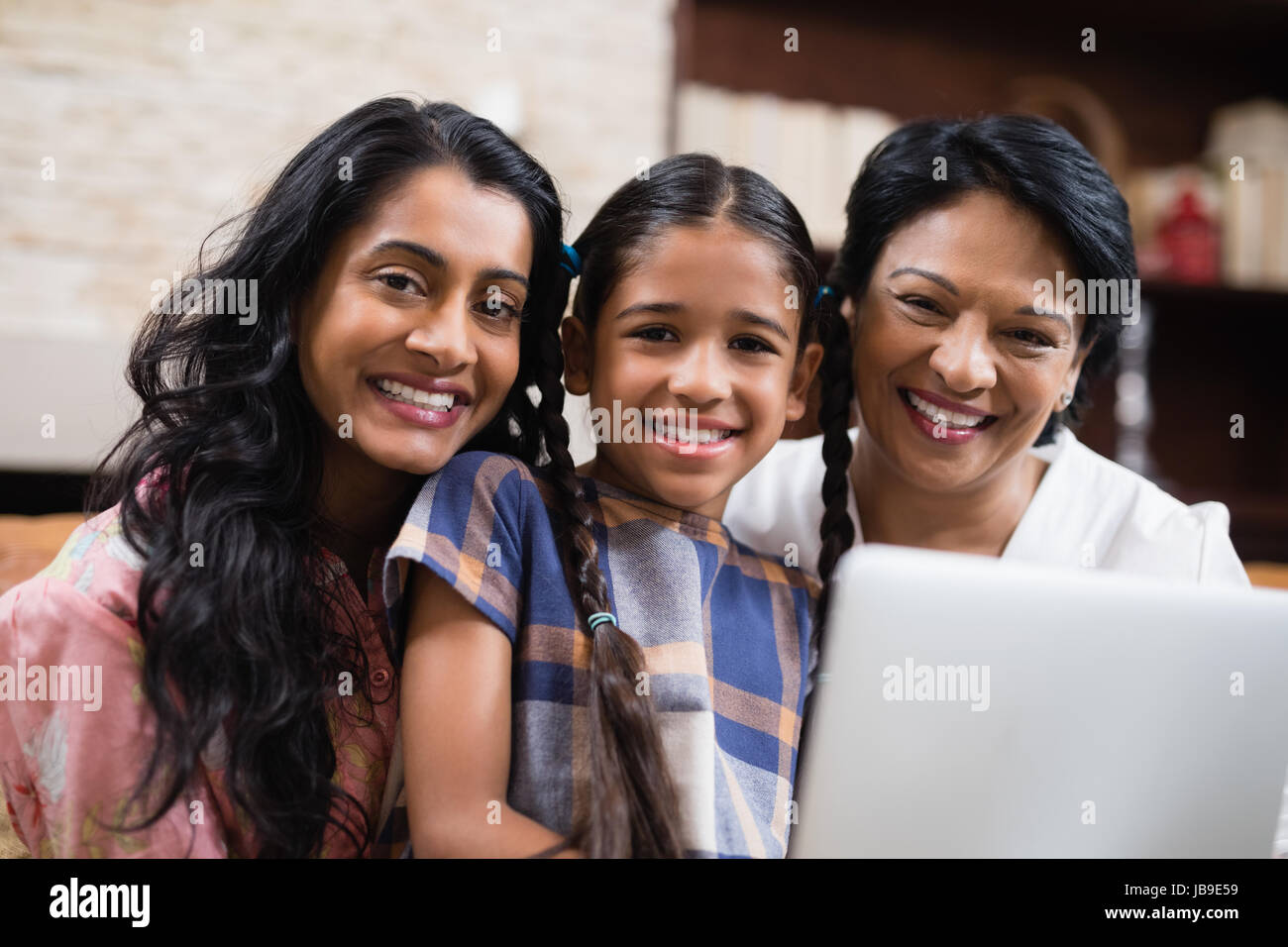 Ritratto sorridente multi-generazione famiglia con portatile a casa Foto Stock