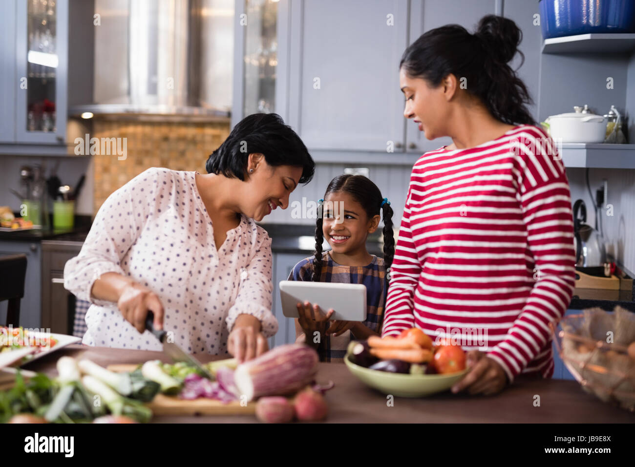 Felice multi-famiglia di generazione di preparare il cibo mentre in piedi in cucina a casa Foto Stock