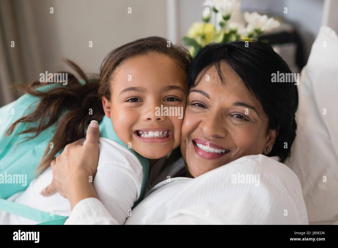 Close up di felice donna matura abbracciando la ragazza sul letto di casa Foto Stock
