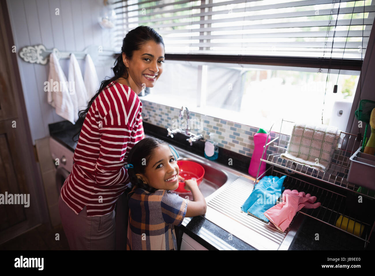 Ritratto di ragazza sorridente aiutando la madre nella cucina di casa Foto Stock