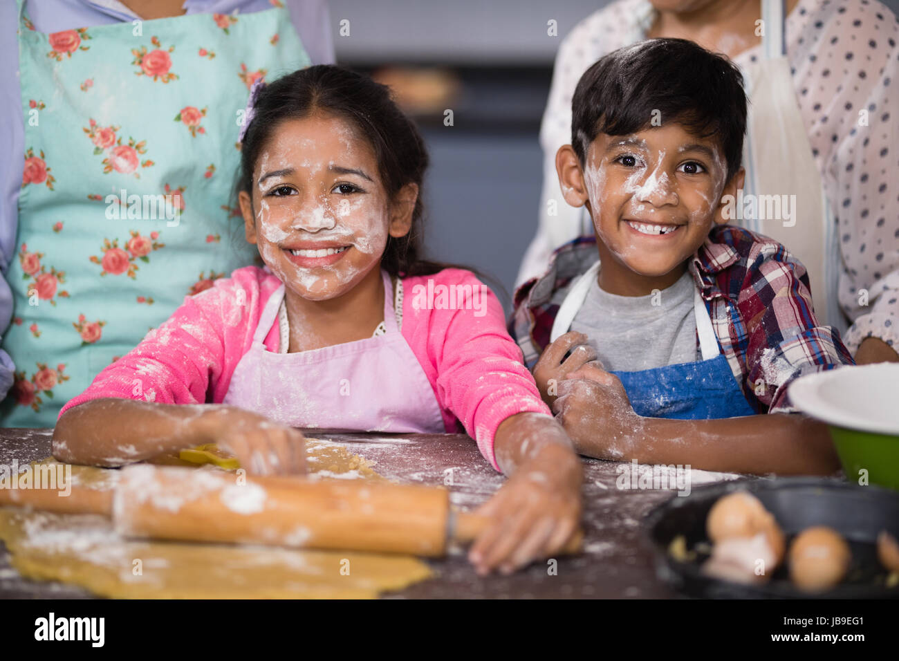 Ritratto di sorridere i fratelli con la farina sulla faccia in piedi in cucina a casa Foto Stock