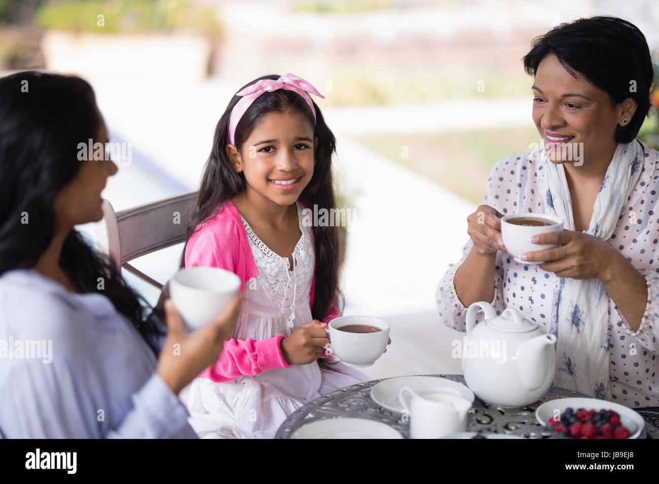 Ritratto di ragazza sorridente avente la prima colazione con la madre e la nonna a casa Foto Stock