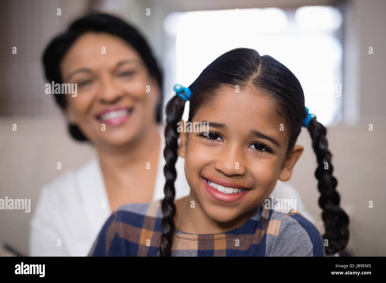 Ritratto di ragazza sorridente con la nonna in background a casa Foto Stock