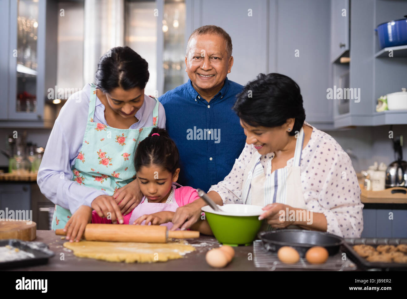 Ritratto di sorridere uomo maturo in piedi con la famiglia nella preparazione degli alimenti in cucina a casa Foto Stock