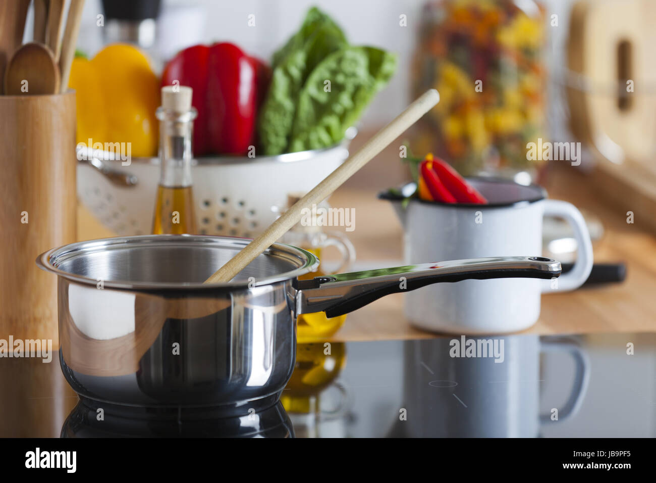 Kochtopf mit Kochlöffel steht auf Kochfeld Foto Stock