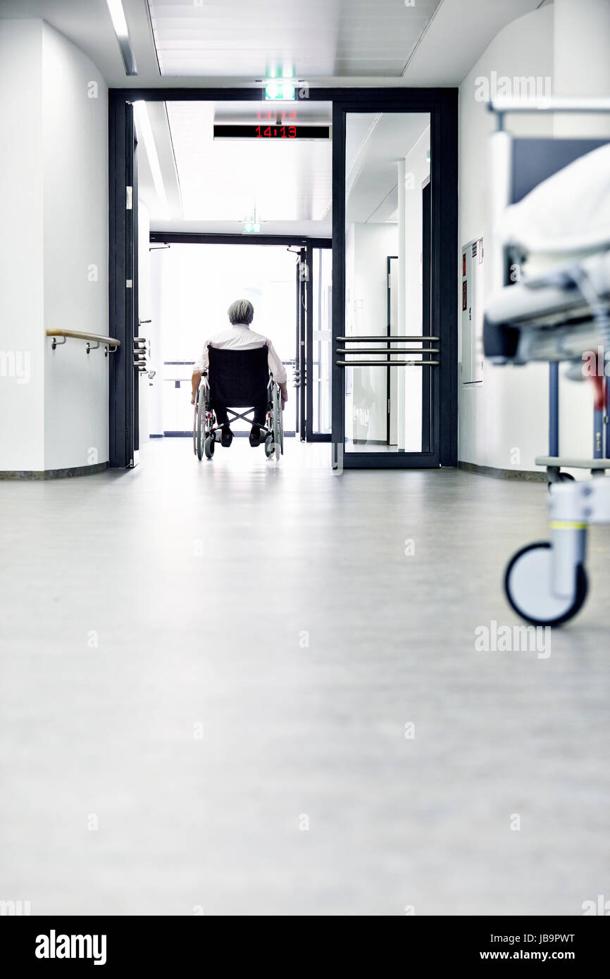 Rollstuhlfahrer im Rollstuhl im Flur mit Tür im Krankenhaus Foto Stock