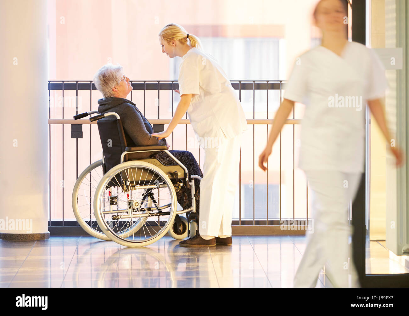 Rollstuhl und Patientin im Krankenhaus mit Krankenschwestern Foto Stock