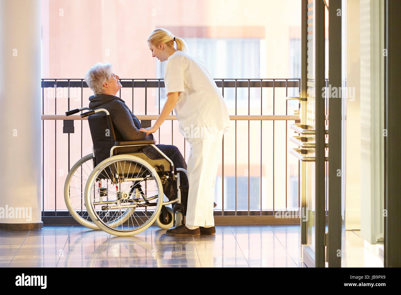 Rollstuhl und Patientin im Krankenhaus mit Krankenschwester Foto Stock