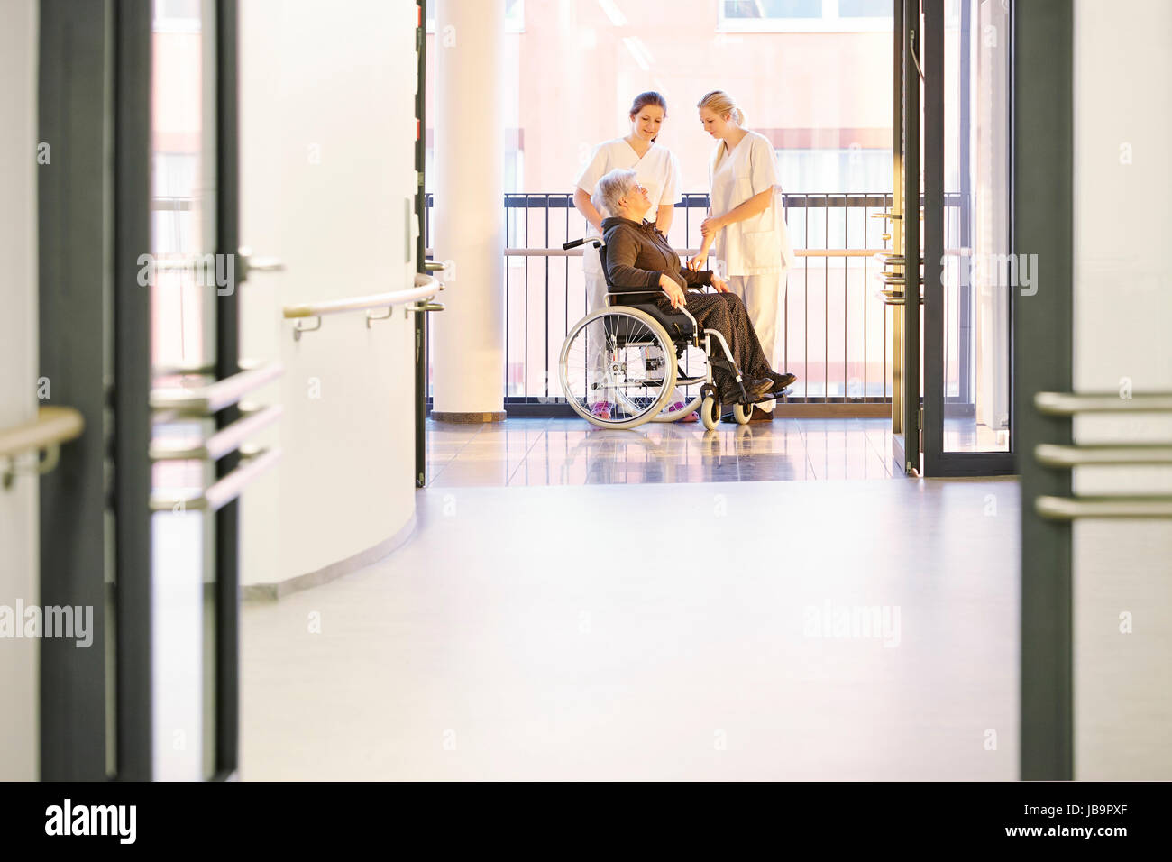 Patientin im Krankenhaus mit Krankenschwestern und Rollstuhl Foto Stock