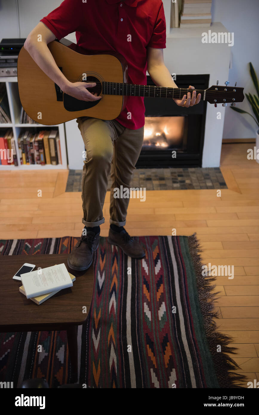 Uomo a suonare la chitarra nel salotto di casa Foto Stock