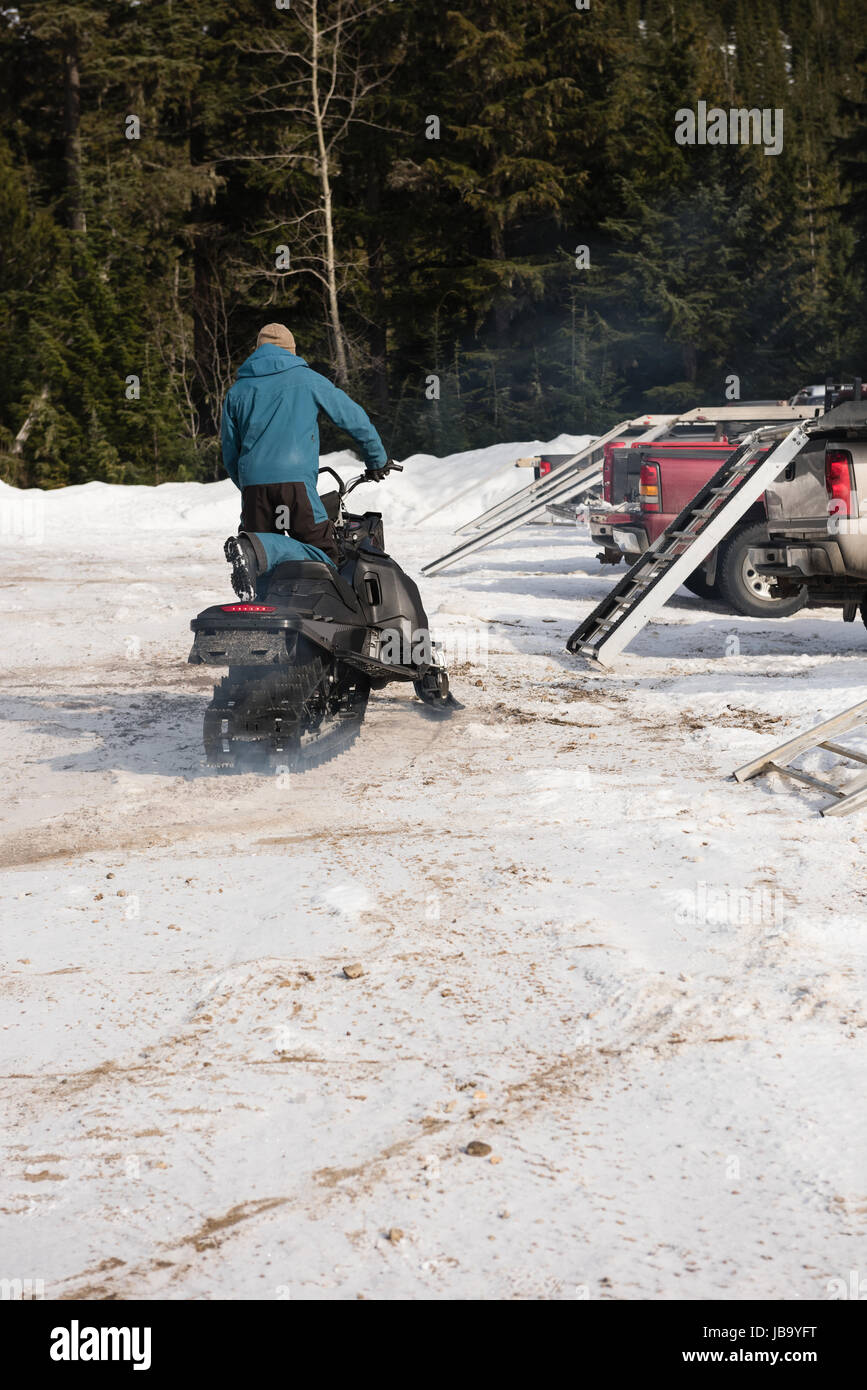 Caricamento uomo motoslitta su van durante il periodo invernale Foto Stock