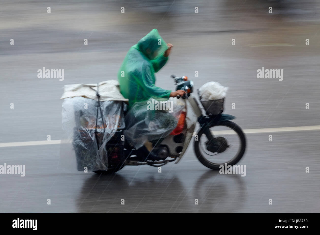 Uomo su scooter a pioggia, Ninh Binh, Vietnam Foto Stock