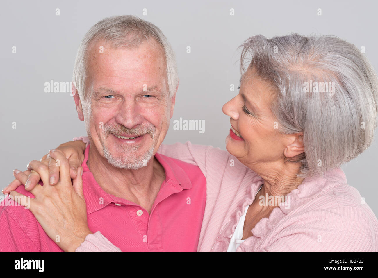 Glückliches Seniorenpaar vor grauem Hintergrund Foto Stock