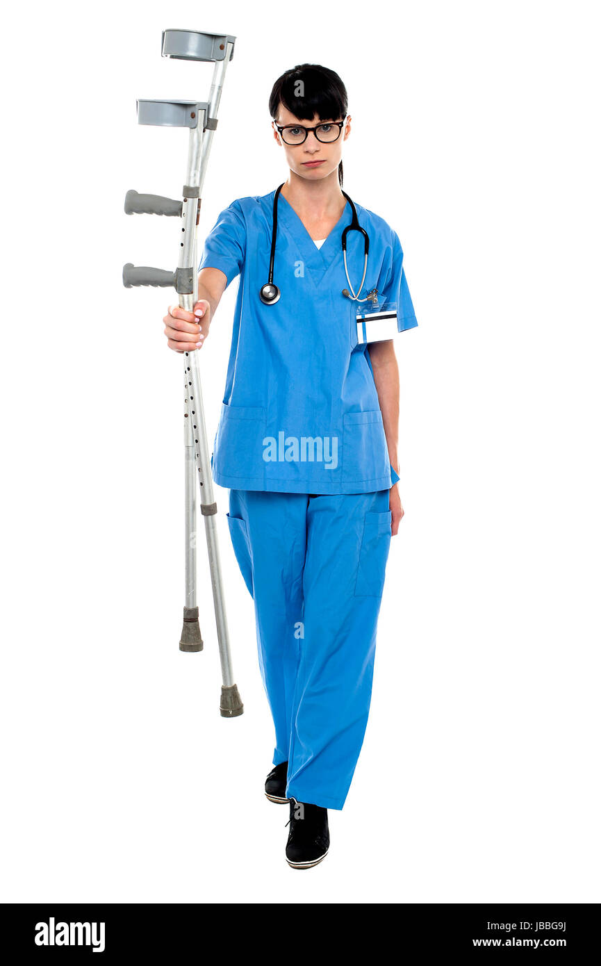 Triste medico tenendo su stampelle in mano e camminare verso la telecamera. Foto Stock