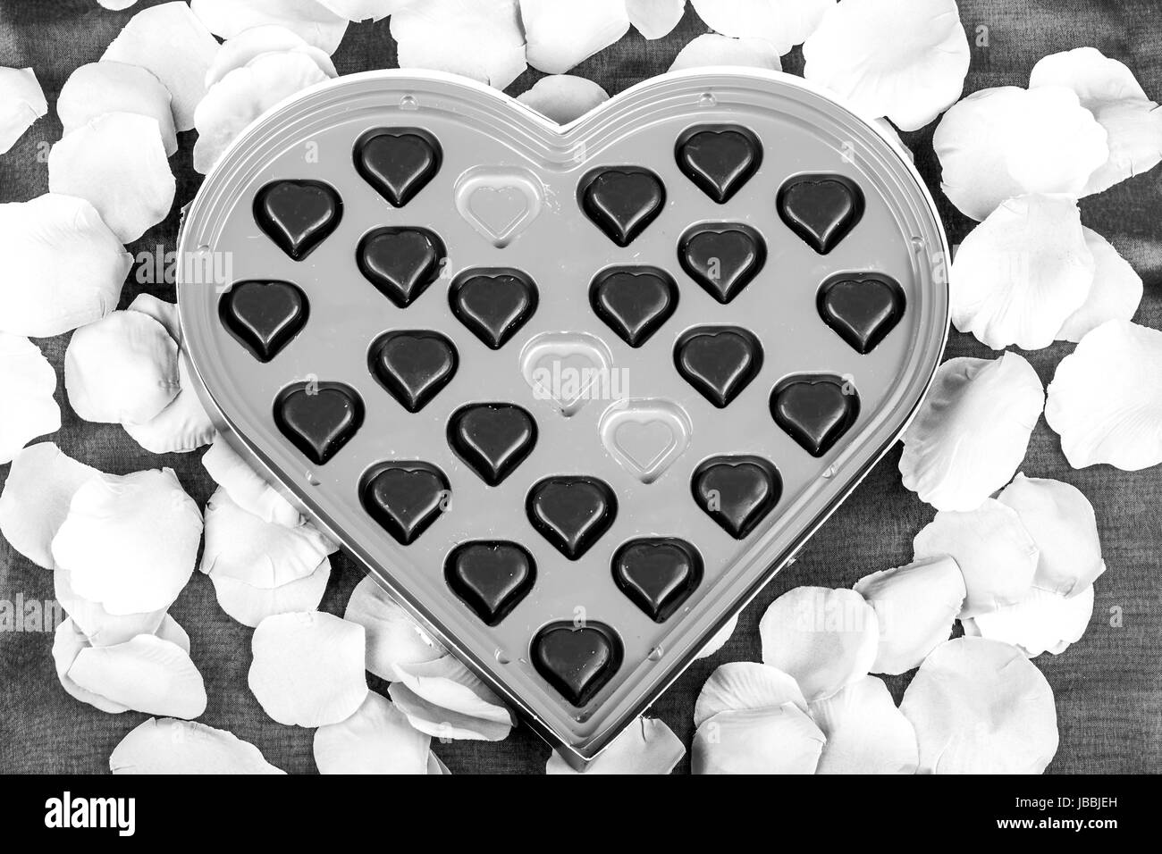 Cuori di cioccolato come Valentino presente con petali di rosa in bianco e nero Foto Stock