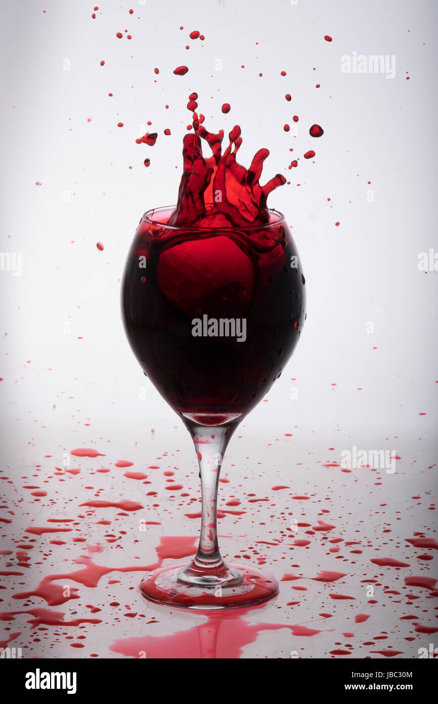 Vino rosso schizzi fuori da un bicchiere Foto Stock