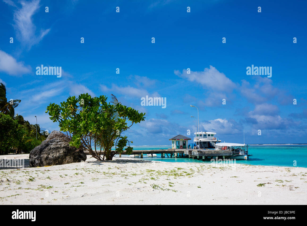 Imbarcazione attraccata ad un molo su un isola delle vacanze alle Maldive. Polvere di sabbia bianca e la lussureggiante vegetazione verde. la locale scuola di immersione opera da questo getto. Foto Stock