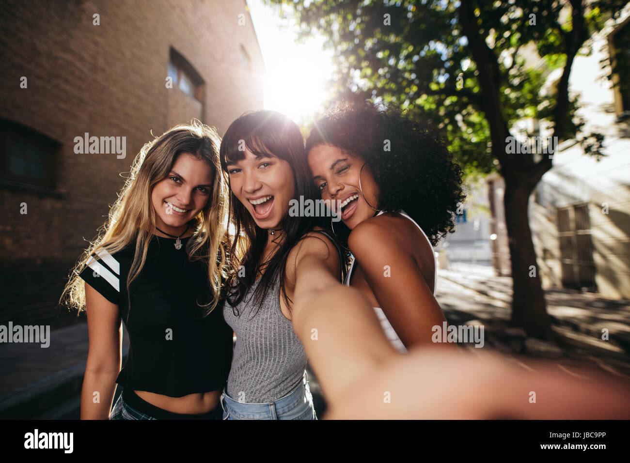 Tre belle ragazze giovani prendendo ritratto di auto mentre appendere fuori città. Multirazziale donne godendo una giornata in giro per la città facendo selfie. Foto Stock