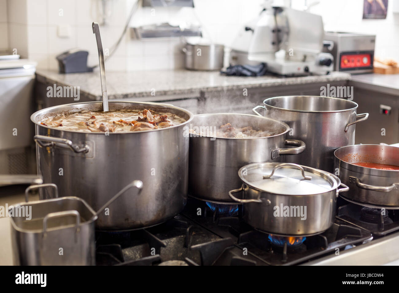 Gastronomie ristorante küche mit kochfeld und dampfenden töpfen beim kochen essen zubereiten cena Foto Stock