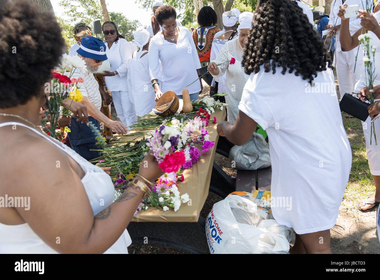 Charleston, Carolina del Sud, Stati Uniti d'America. Decimo Giugno, 2017. I discendenti di schiavi africani portati a Charleston nel passaggio intermedio selezionate fiori di gettare in un oceano di onorare i loro parenti persi durante una cerimonia di commemorazione a Fort Moutrie Monumento Nazionale Giugno 10, 2017 in Sullivan's Island, nella Carolina del Sud. Il passaggio intermedio si riferisce al commercio triangolare in cui milioni di africani sono stati spediti verso il Nuovo Mondo come parte dell'Atlantico il commercio degli schiavi. Una stima di 15% degli africani morti in mare e notevolmente più nel processo di cattura e di trasporto. Credito: Planetpix/Alamy Live ne Foto Stock