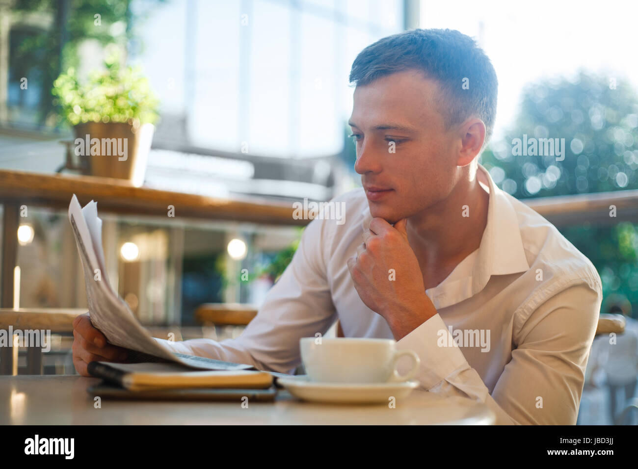 Considerato l uomo leggendo un giornale in una street cafe a pranzo. Concetto di gente di affari. Foto Stock