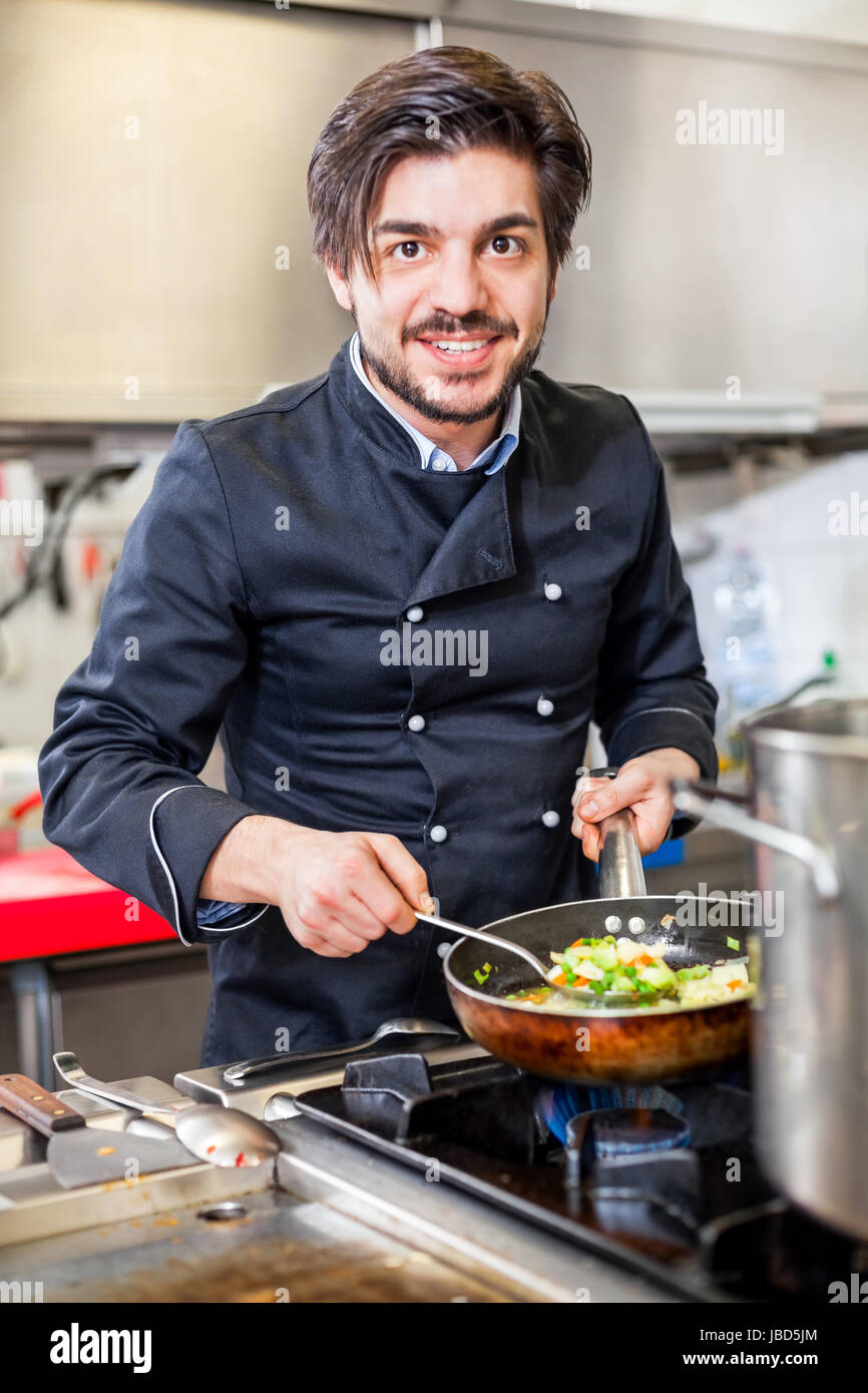 Junger erwachsener chefkoch in der ristorante küche beim kochen am zubereitung mandria Foto Stock