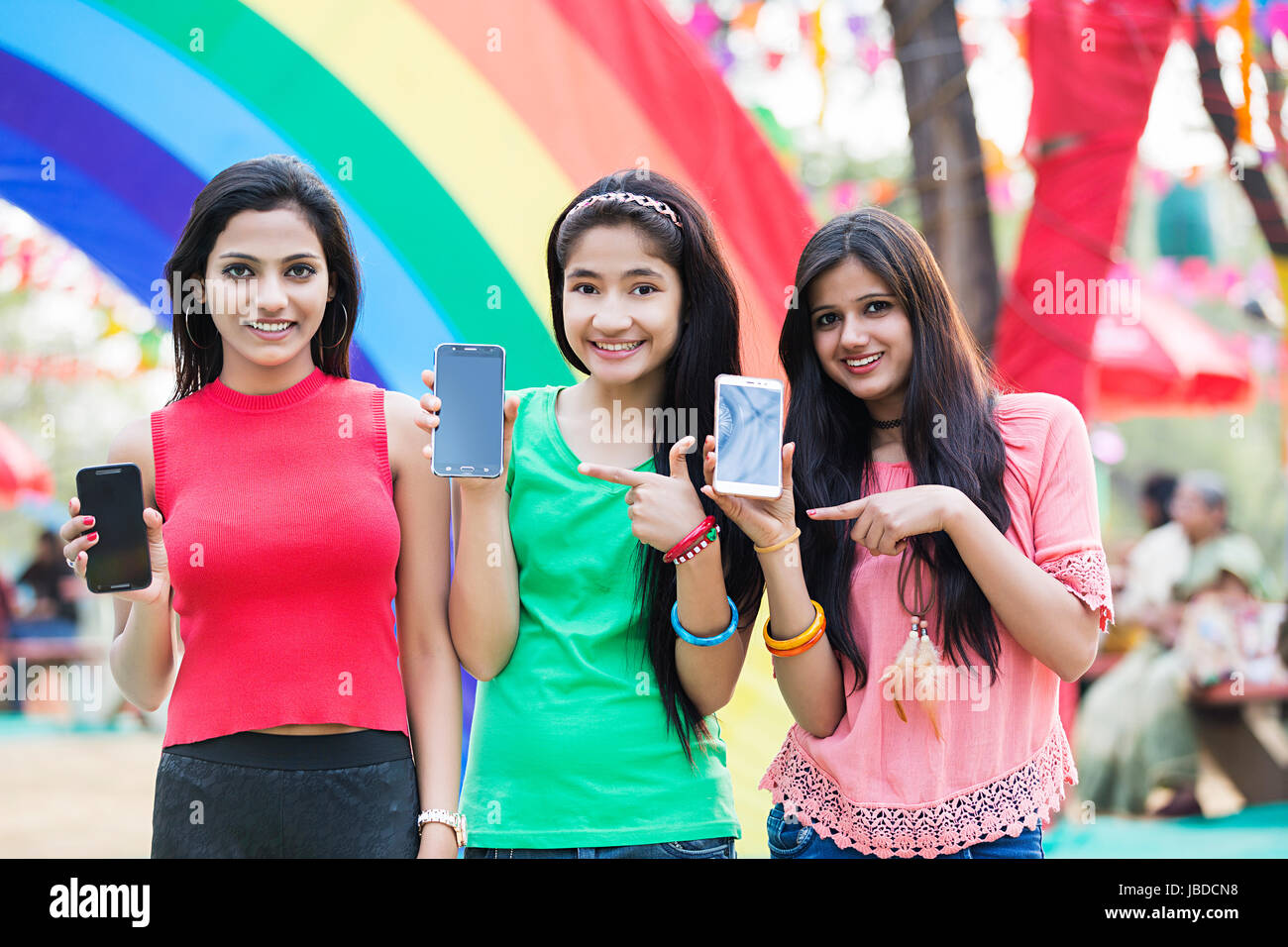 3 ragazze giovani amici che mostra il telefono cellulare rivolta godere di mela Foto Stock