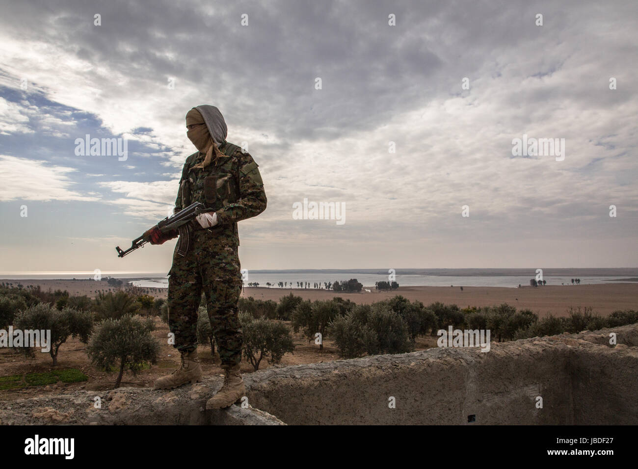 Chris huby / le pictorium - Siria / rojava - ira dell'Eufrate - 02/01/2017 - rojava - Siria - rojava - Dic16 e Jan17 - un curdo soldato ypg pone di fronte l'Eufrate fase finale per i curdi nella zona appena prima della diga tapqa. Una volta fatto, essi possono attaccare raqqa. Foto Stock