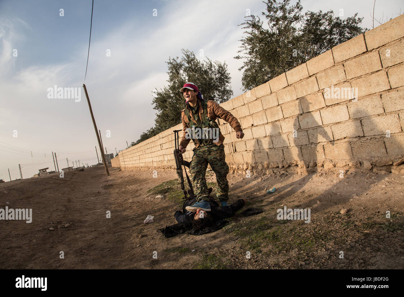Chris Huby / Le Pictorium - Siria / Rojava - ira dell'Eufrate - 02/01/2017 - Rojava - Siria ROJAVA / DEC16 - Jan17. Villaggio Mahmudli. Un arabe SDF soldato è camminare su un ISIS corpo morto. Foto Stock