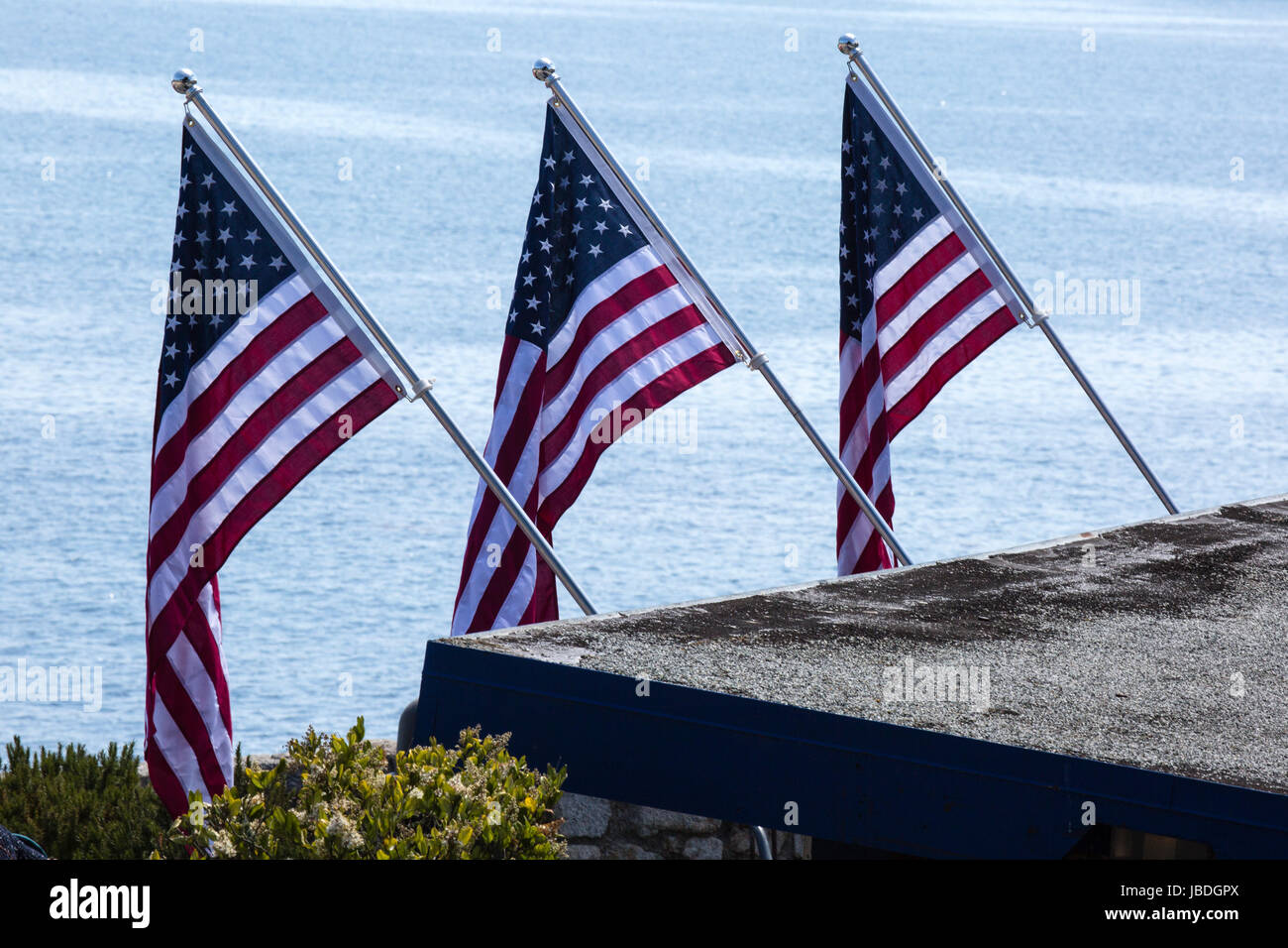 Tre Stati Uniti bandiere in Pacific Grove, California, sull'Oceano Pacifico. Foto Stock