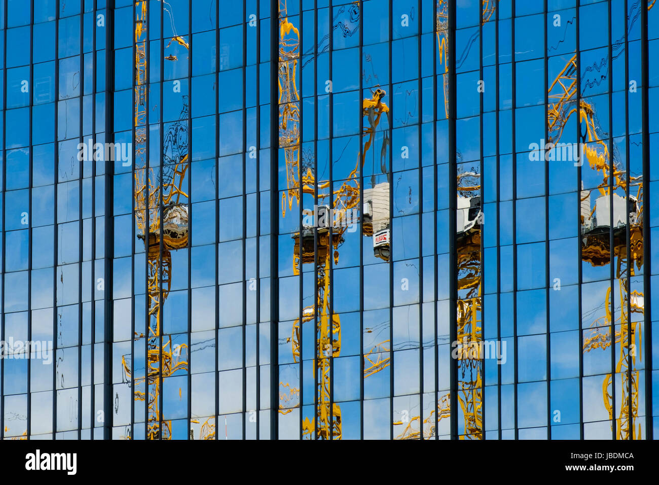 La riflessione di molte gru edili in vetro moderna facciata in vetro Foto Stock