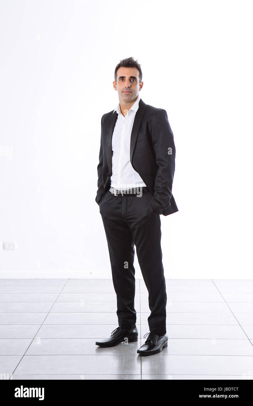 Un 35 - 40 anni con suit office uomo sorridente cool look moderno mani nelle tasche studio shot su uno sfondo bianco pieno shot Foto Stock