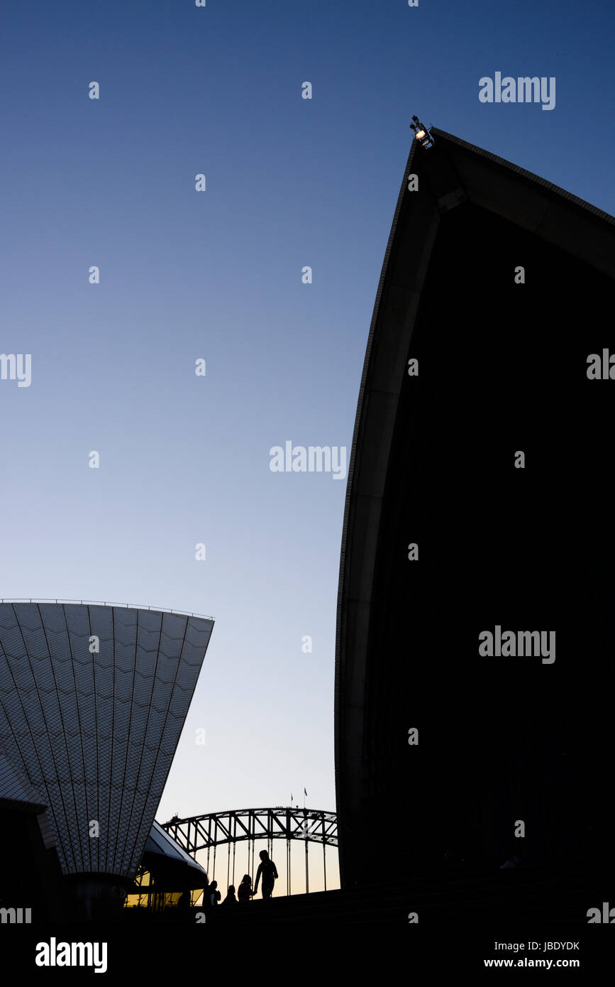I turisti ad esplorare la Sydney Opera House al tramonto. Il gigante di vele sollevarsi oltre il piazzale antistante, rimpicciolendo i turisti sulle scale di seguito. Foto Stock