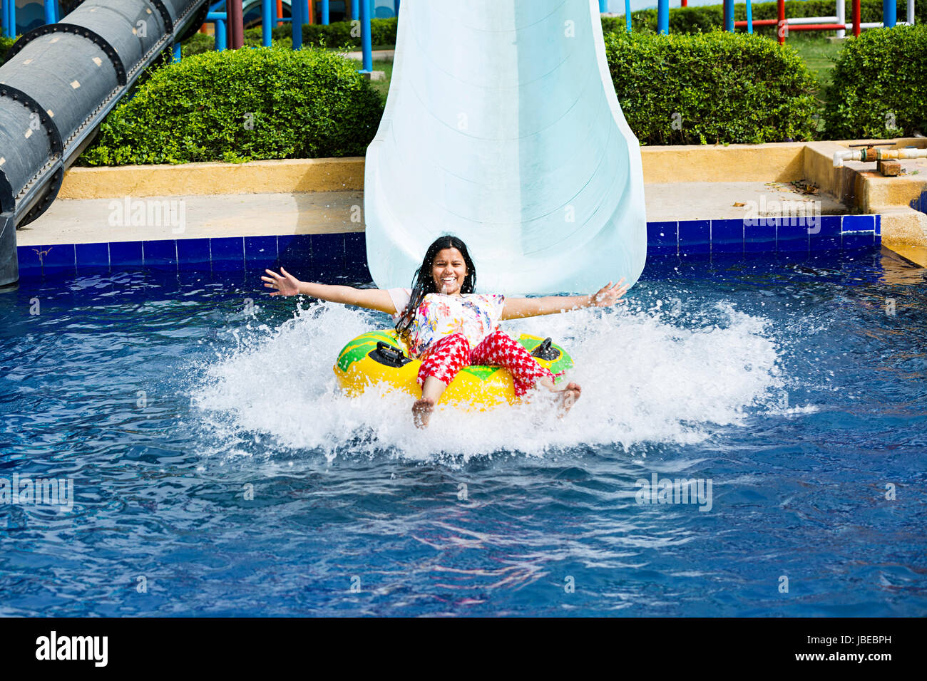 Happy 1 giovane donna di spruzzi di scorrimento parco acquatico con piscina Foto Stock