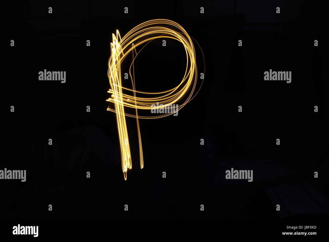 Oro lettera P, luce fotografia pittura, alphabet series contro uno sfondo nero Foto Stock