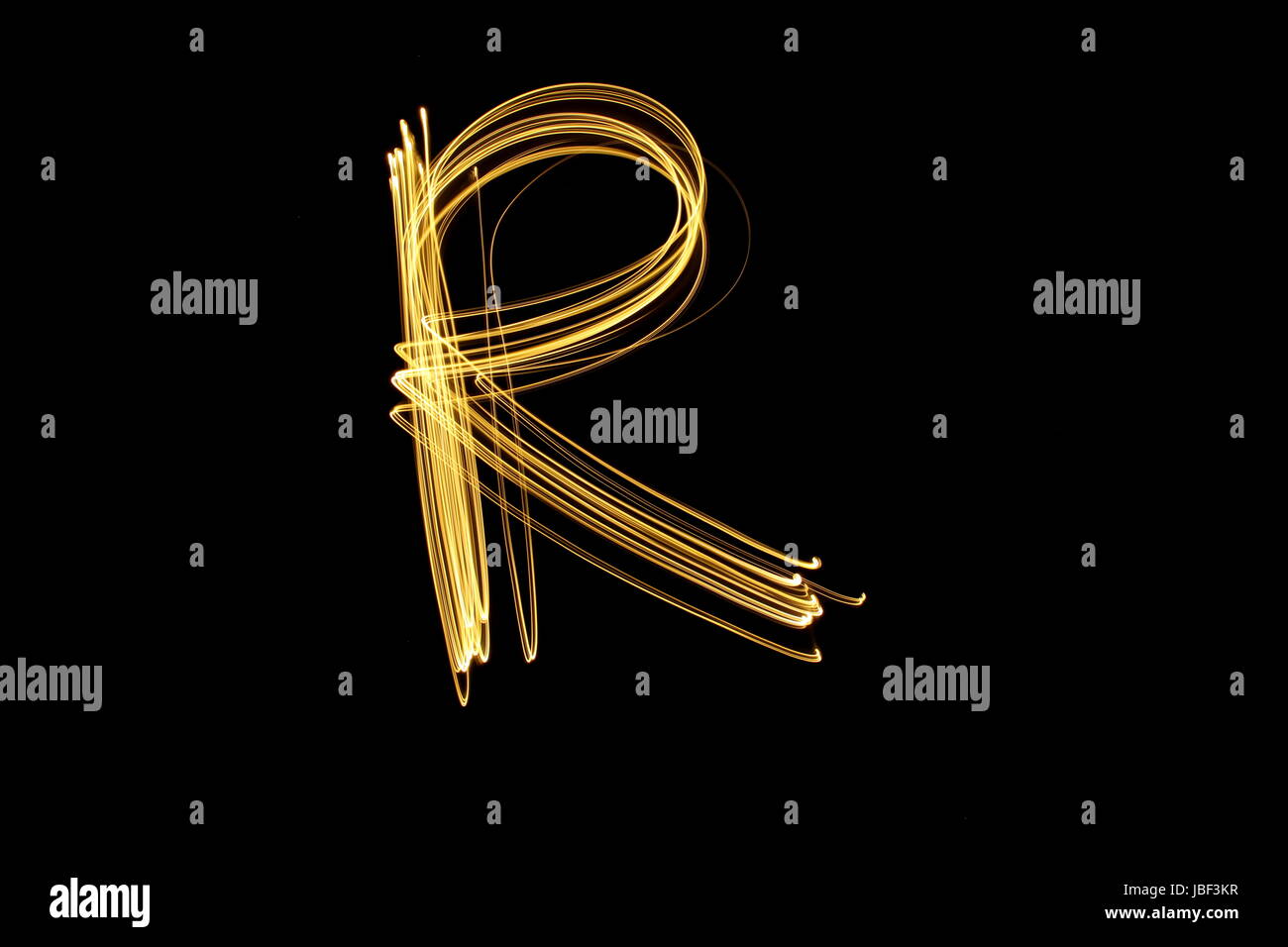 Oro lettera R, luce fotografia pittura, alphabet series contro uno sfondo nero Foto Stock