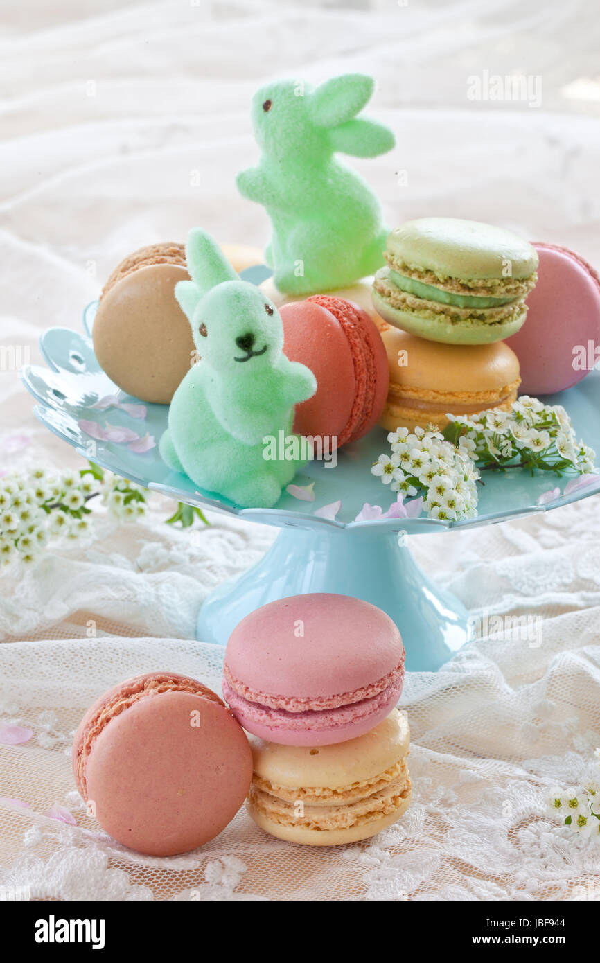 Bunte franzoesische Macarons auf blauem Teller und kleine Osterhasen Foto Stock