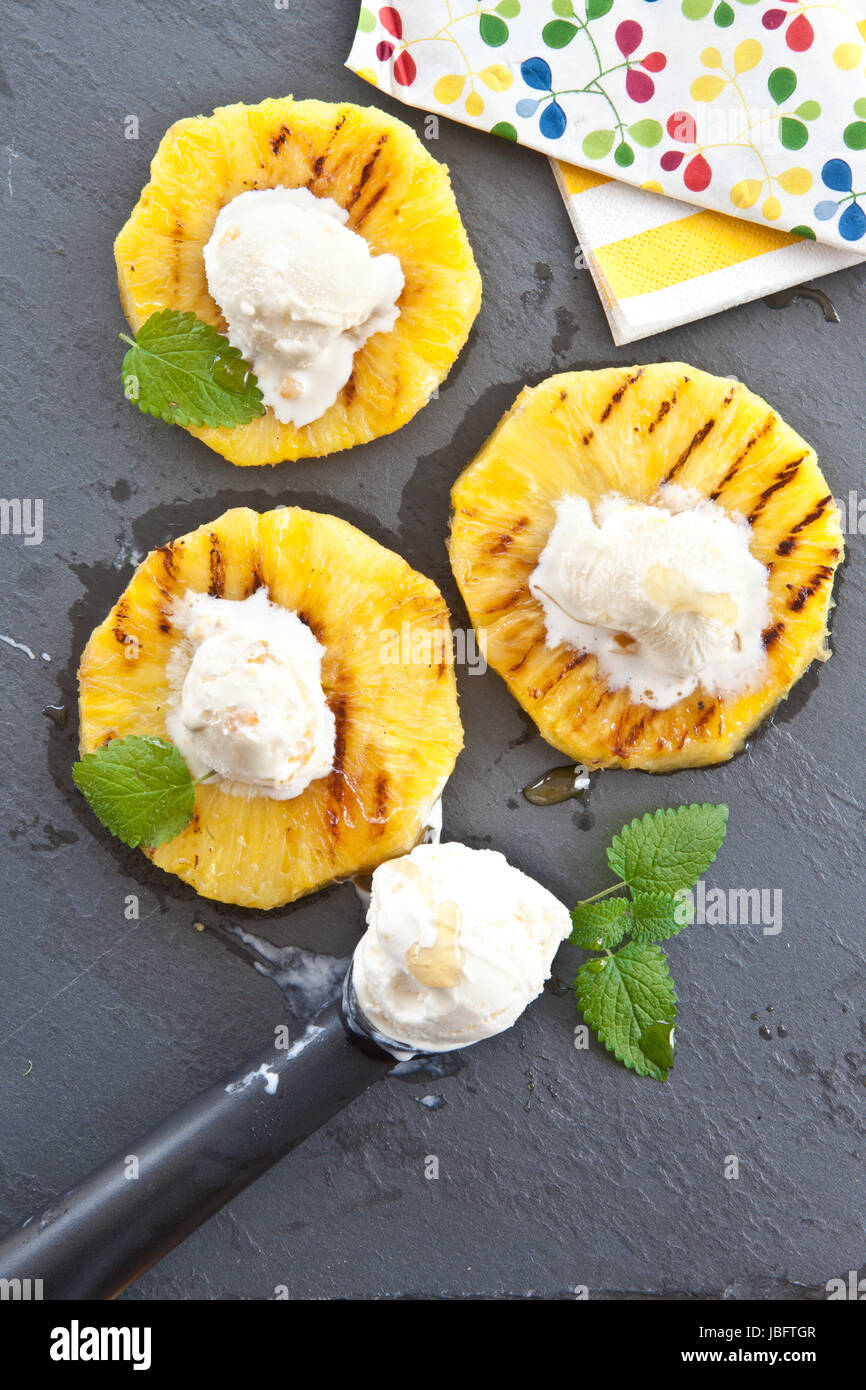 Gegrillte Ananasringe Eiscremekugeln mit Honig und auf Schieferplatte Foto Stock