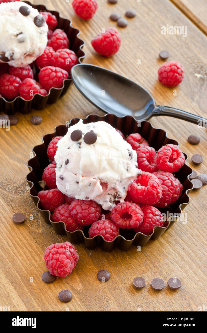 Eis mit Himbeeren und Schokolade auf rustikalem Holz Foto Stock