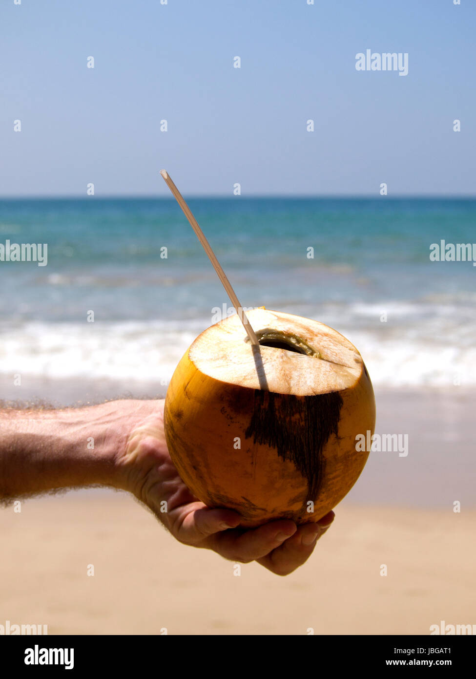 Uomo con drink di noce di cocco con una cannuccia in mano Foto Stock