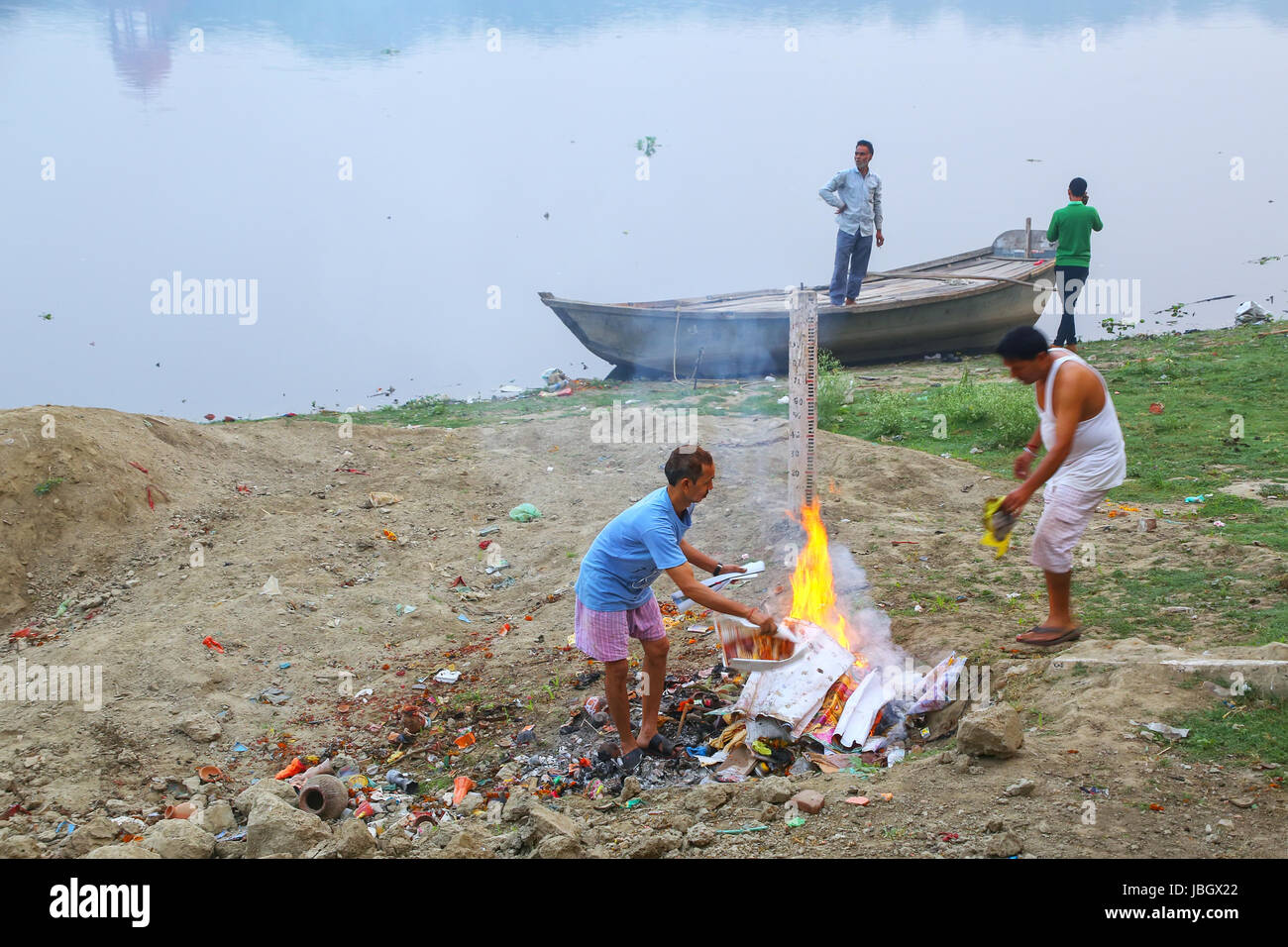 Gli uomini locali burning garbage sulla banca del fiume Yamuna, Agra, Uttar Pradesh, India. Taj Mahal è stato designato come un Sito Patrimonio Mondiale dell'UNESCO nel 1983. Foto Stock