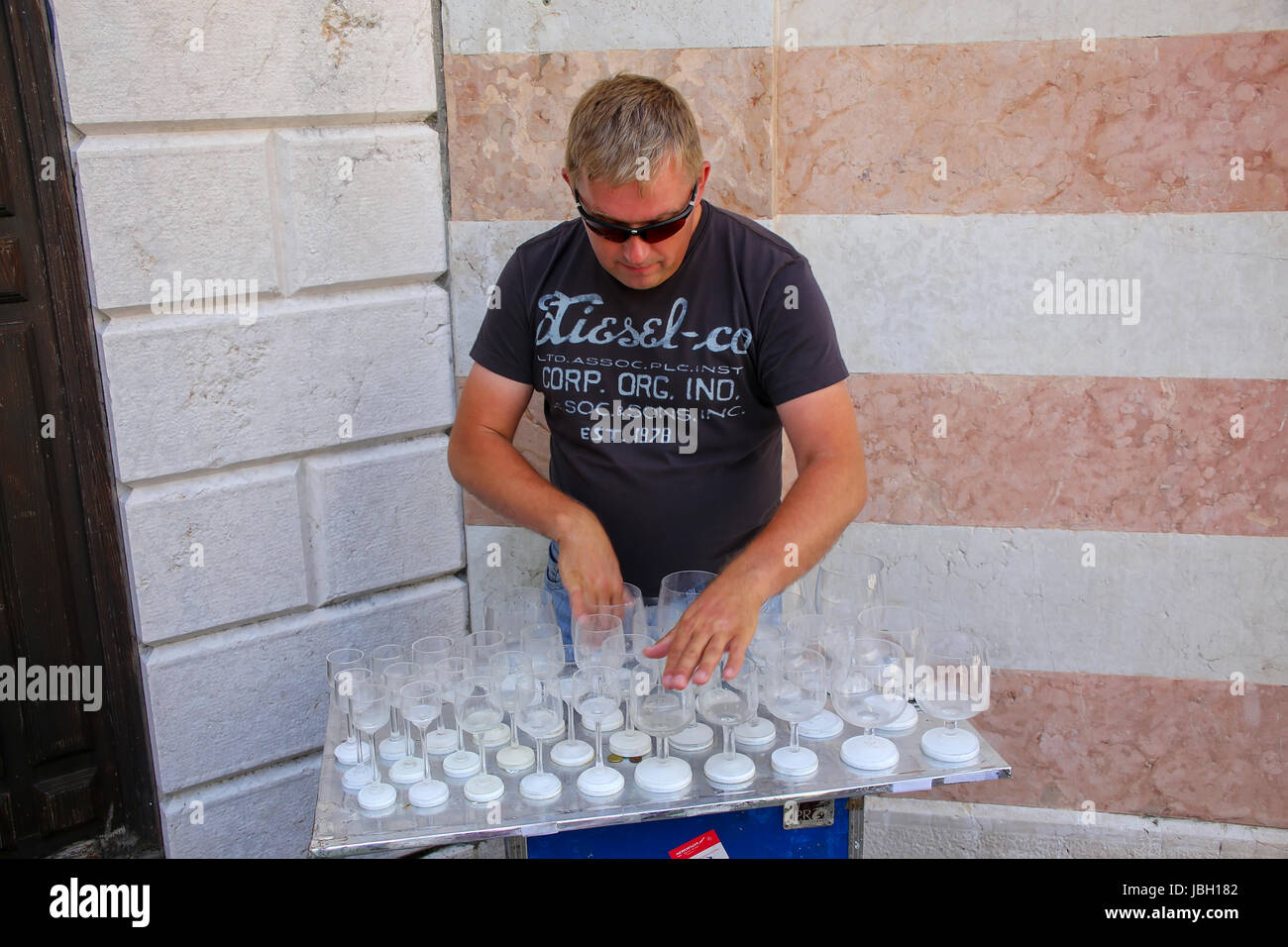 L'uomo la riproduzione di musica su acqua folled bicchieri in Venezia, Italia. Venezia è una delle più importanti destinazioni turistiche nel mondo per la sua celebre un Foto Stock