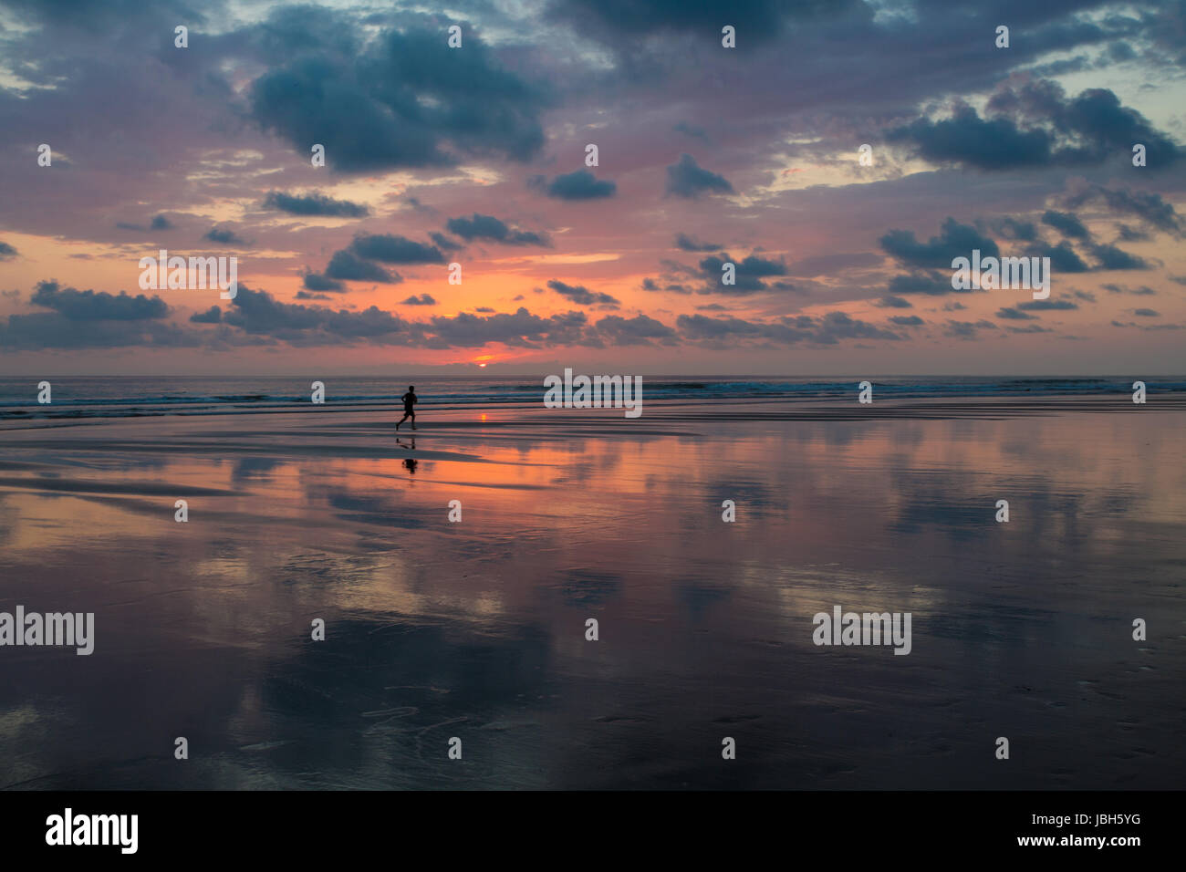 Vista al tramonto sulla spiaggia di Matapalo con silhouette di un uomo che fa il suo jogging, Costa Rica. Matapalo si trova nel sud della costa del Pacifico. Le principali attrazioni sono il surf e eco-turismo, Costa Rica 2013. Foto Stock