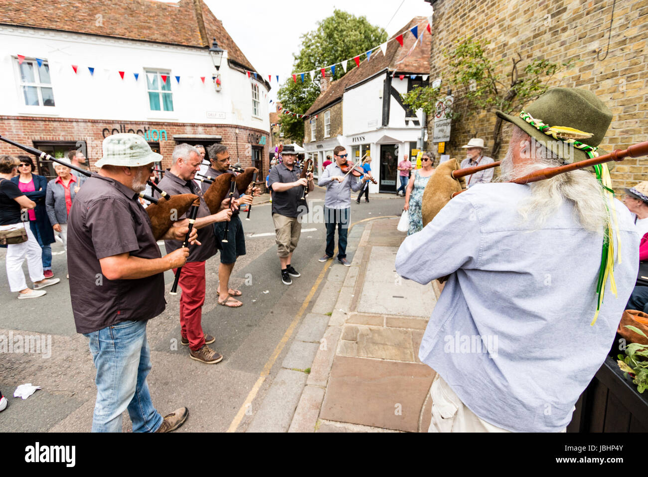 Le Weekend di eventi in città a Sandwich Kent. Un gruppo di uomini in piedi sulla strada a suonare cornamusa medievale con uno a suonare il violino, guardato da piccolo pubblico. Foto Stock