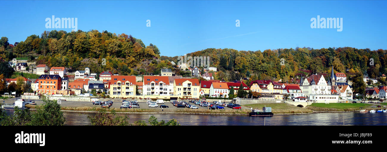 Idyllischer Kurort an der Elbe in der Sächsischen Schweiz in Deutschland, schöne Häuser und bunte Laubwälder, im Vordergrund die Elbe, panorama idilliaco cittadina termale sull'Elba nella Svizzera sassone in Germania di belle case e coloratissimi boschi di latifoglie, in primo piano il fiume Elba, panoramica Foto Stock