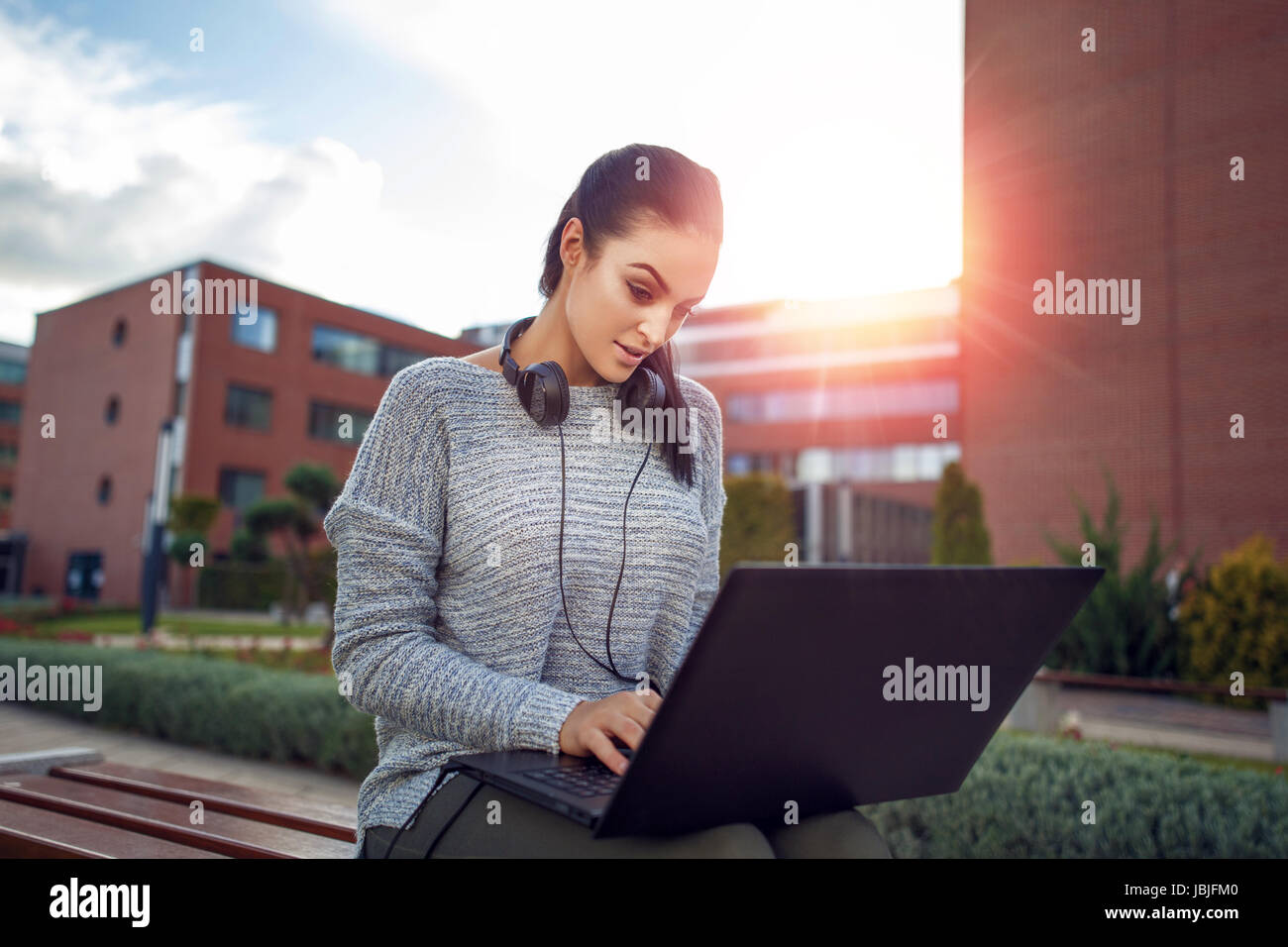 Donna digitando su laptop all'aperto nel parco cittadino e tecnologia wireless Foto Stock