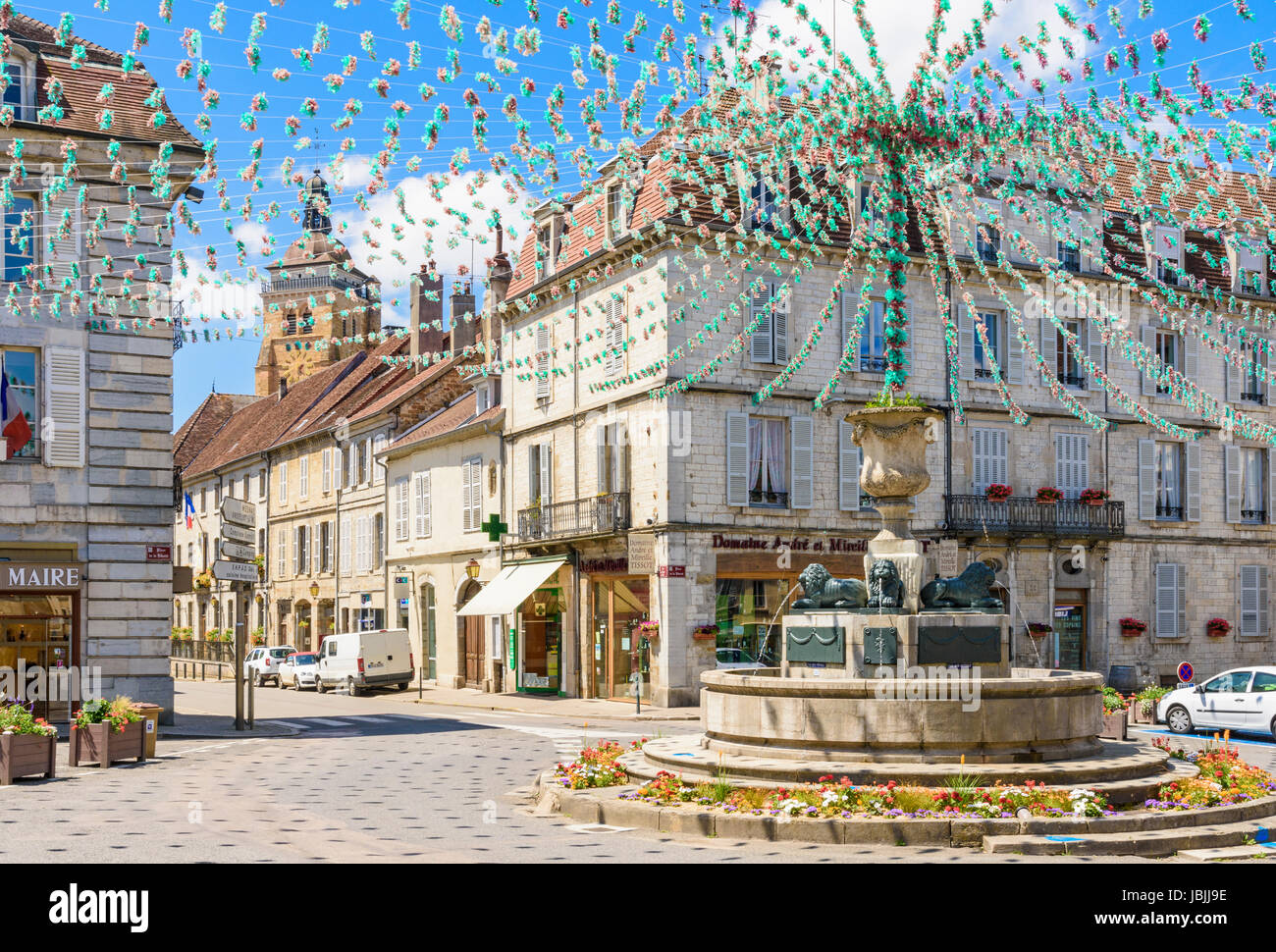 Fontana centrale e degli edifici circostanti in Place de la Liberté, decked out per una festa, Arbois, Giura, Francia Foto Stock