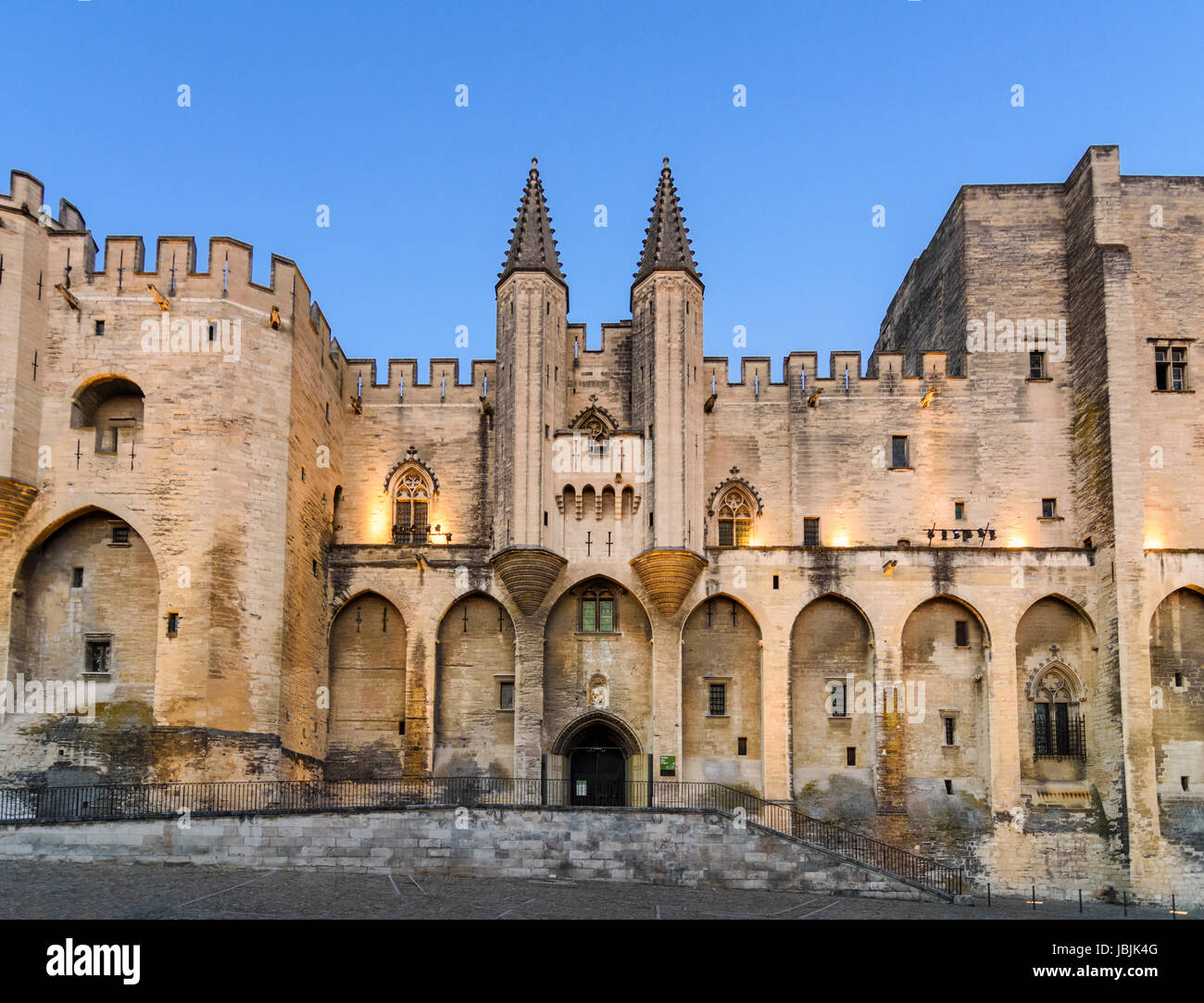 Panorami notturni del gotico doppia facciata turrito del Palais Neuf, Palais des Papes, la Piazza del Palazzo, Avignon, Francia Foto Stock